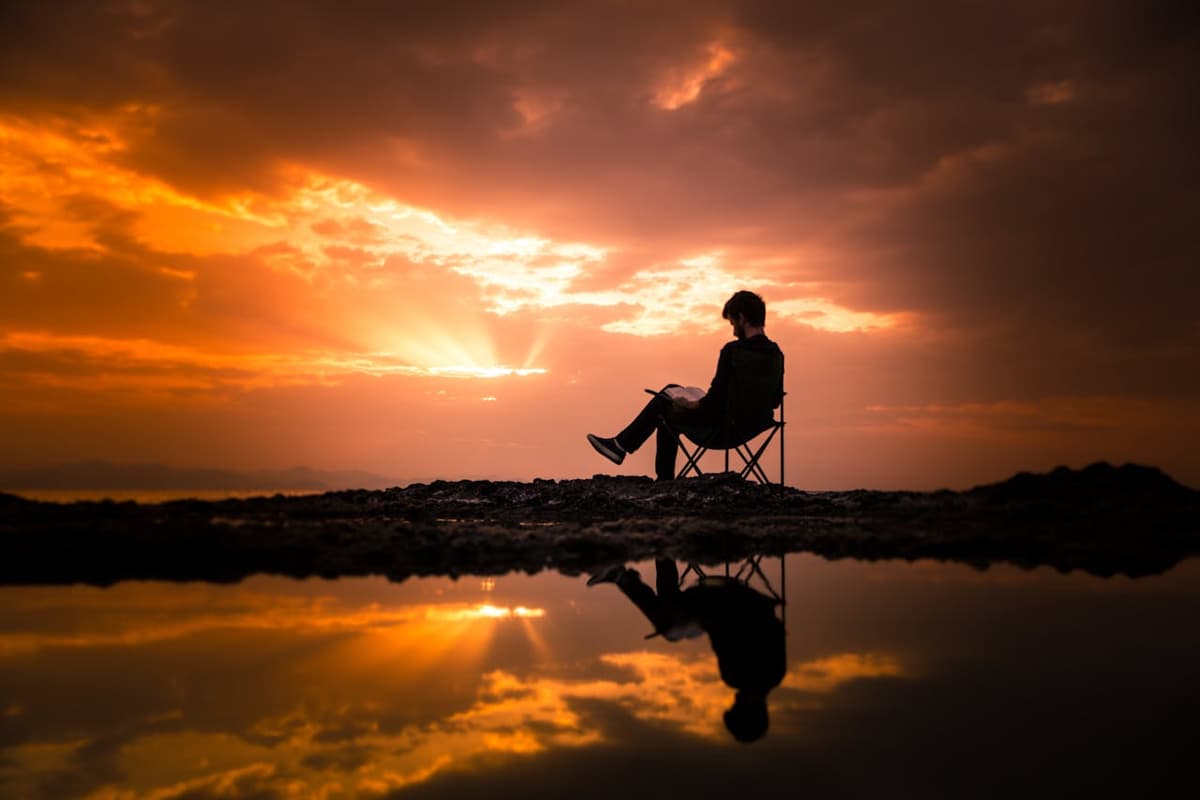 Foto de EYÜP BELEN: https://www.pexels.com/pt-br/foto/foto-de-um-homem-sentado-em-uma-cadeira-de-acampamento-durante-o-amanhecer-1428626/