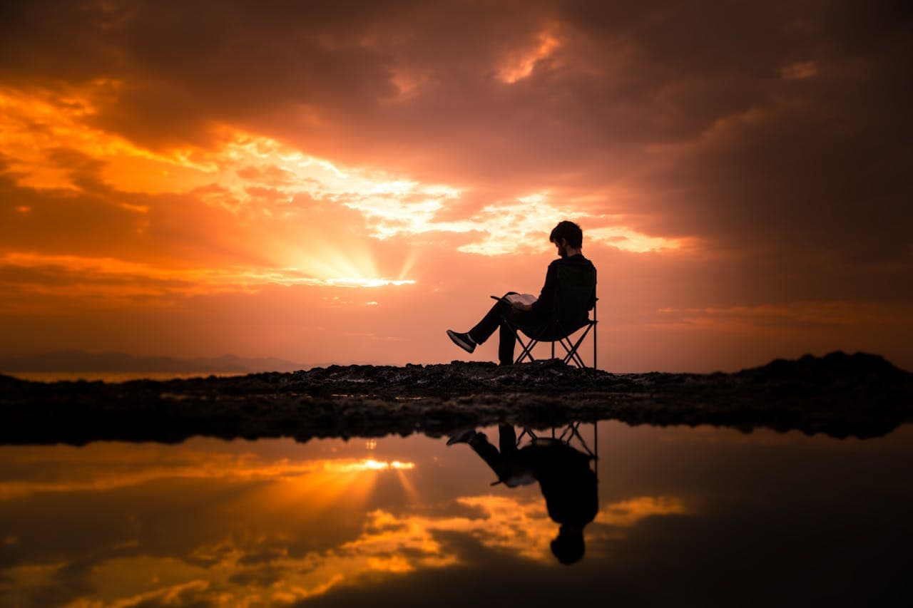 Foto de EYÜP BELEN: https://www.pexels.com/pt-br/foto/foto-de-um-homem-sentado-em-uma-cadeira-de-acampamento-durante-o-amanhecer-1428626/